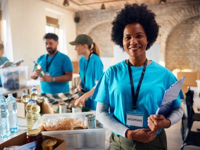 Happy African American woman working as volunteer donation center and looking at camera.