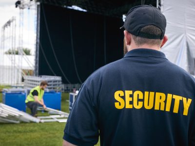 Rear View Of Security Team At Outdoor Stage For Music Festival Or Concert